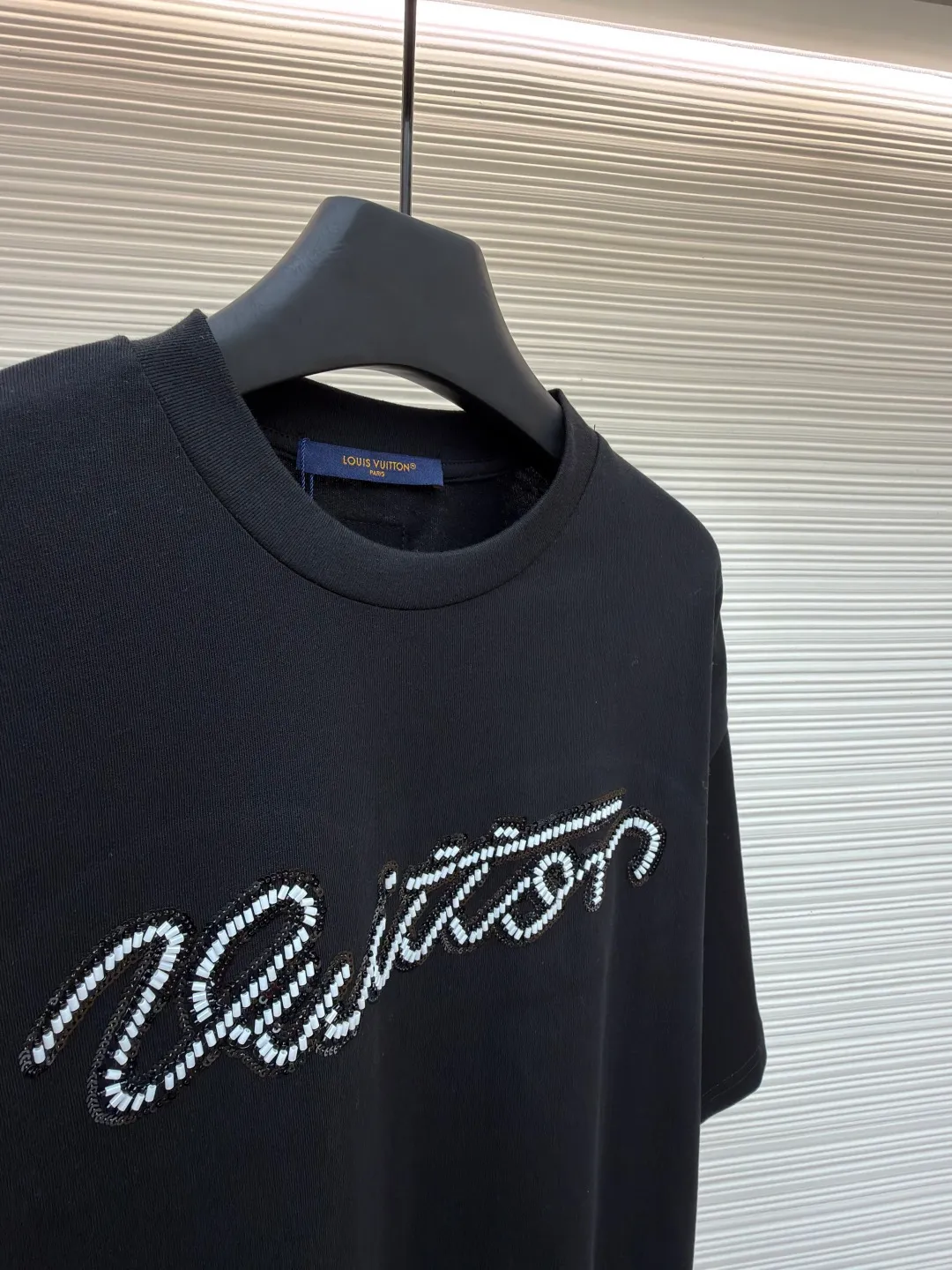 LOUIS VUITTON round neck beaded embroidered short-sleeved T-shirt ●Original version: purchased and developed by 11353 ●Item number: 1681544-A15 ●Material: cotton fabric ●Technology: beading ●Color: black ●Version: fitted version ●Weight: about 310 grams ●Size: XS-S-M-L ●Description: This black T-shirt is made of 100% High-quality cotton fabric, soft to the touch, skin-friendly and breathable. The round neck design fits the neck line and is neatly cut, presenting a classic and simple silhouette. The word "Vuitton" on the chest is the highlight of the entire work: using hand-beading technology, each tiny bead is carefully arranged by craftsmen and fixed on the fabric at precise spacing and angles, forming smooth curves and a full three-dimensional sense. This process not only gives the letters a delicate luster, but also adds to the overall texture and high-end feel. The stitching on the body is even and neat, about 12 stitches per inch, ensuring a solid structure and not easily deformed. The hem and cuffs are smooth and neat, and the edges are clean and neat, reflecting the exquisite craftsmanship of clothing. The overall style presents a low-key luxury style, which is not only suitable for daily wear, but also shows quality and taste in the details. The overall wiring is straight and delicate, the fabric is comfortable and soft, and the color is consistent without color difference. It can be matched with the same style to create a fashionable look and control various occasions. Customized accessories, complete with three standards, same style for men and women!